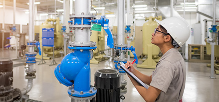 worker with clipboard and pen inspecting an air compressor