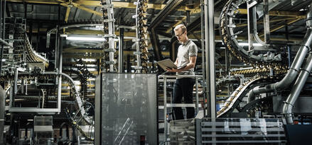 Mobil engineer standing with a computer in a factory